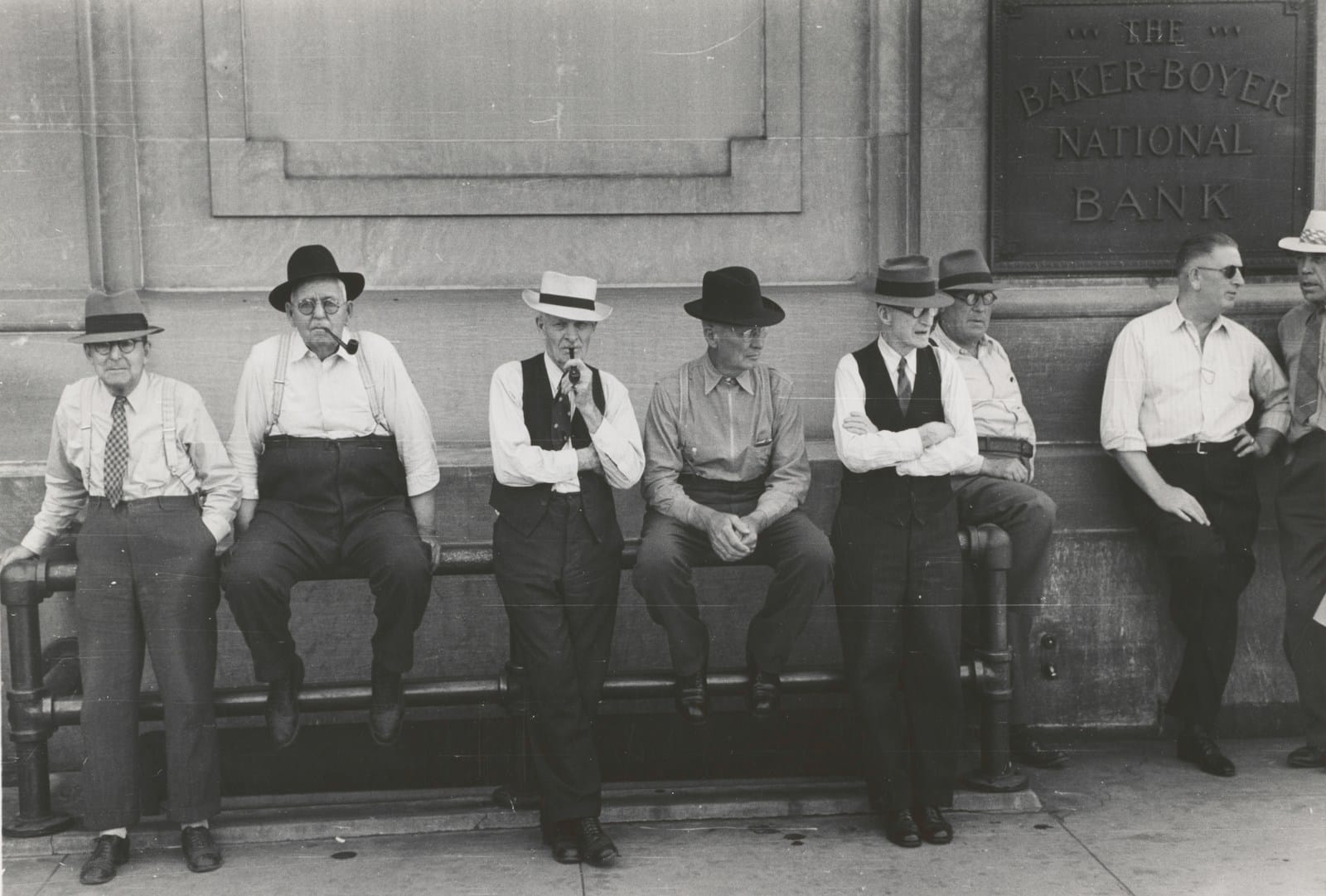 men leaning and sitting on metal railing