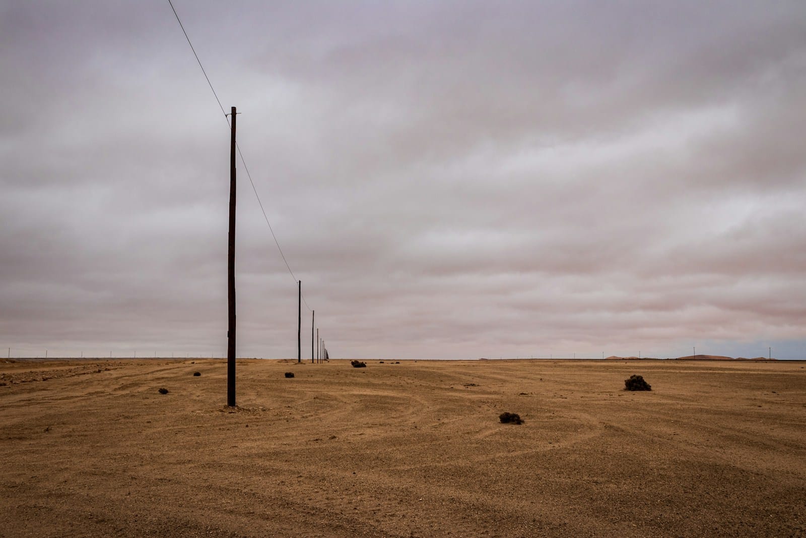 brown field with black metal pole under gray clouds